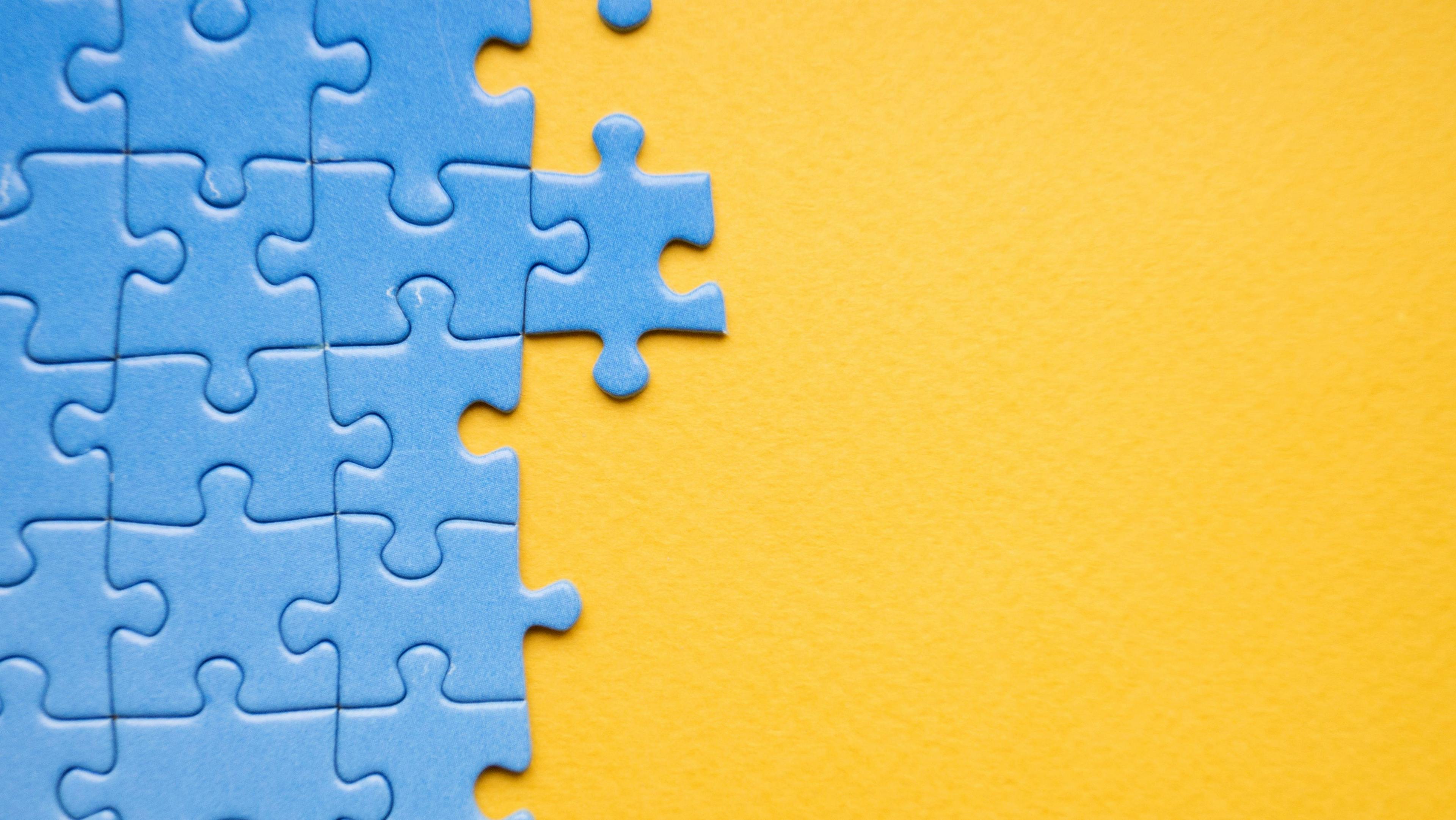 headless CMS - blue puzzle being solved on a yellow background
